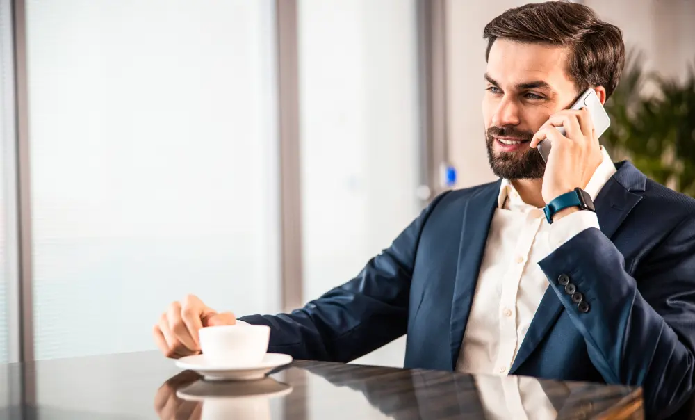 Young man calm and at ease at work on the phone drinking tea.